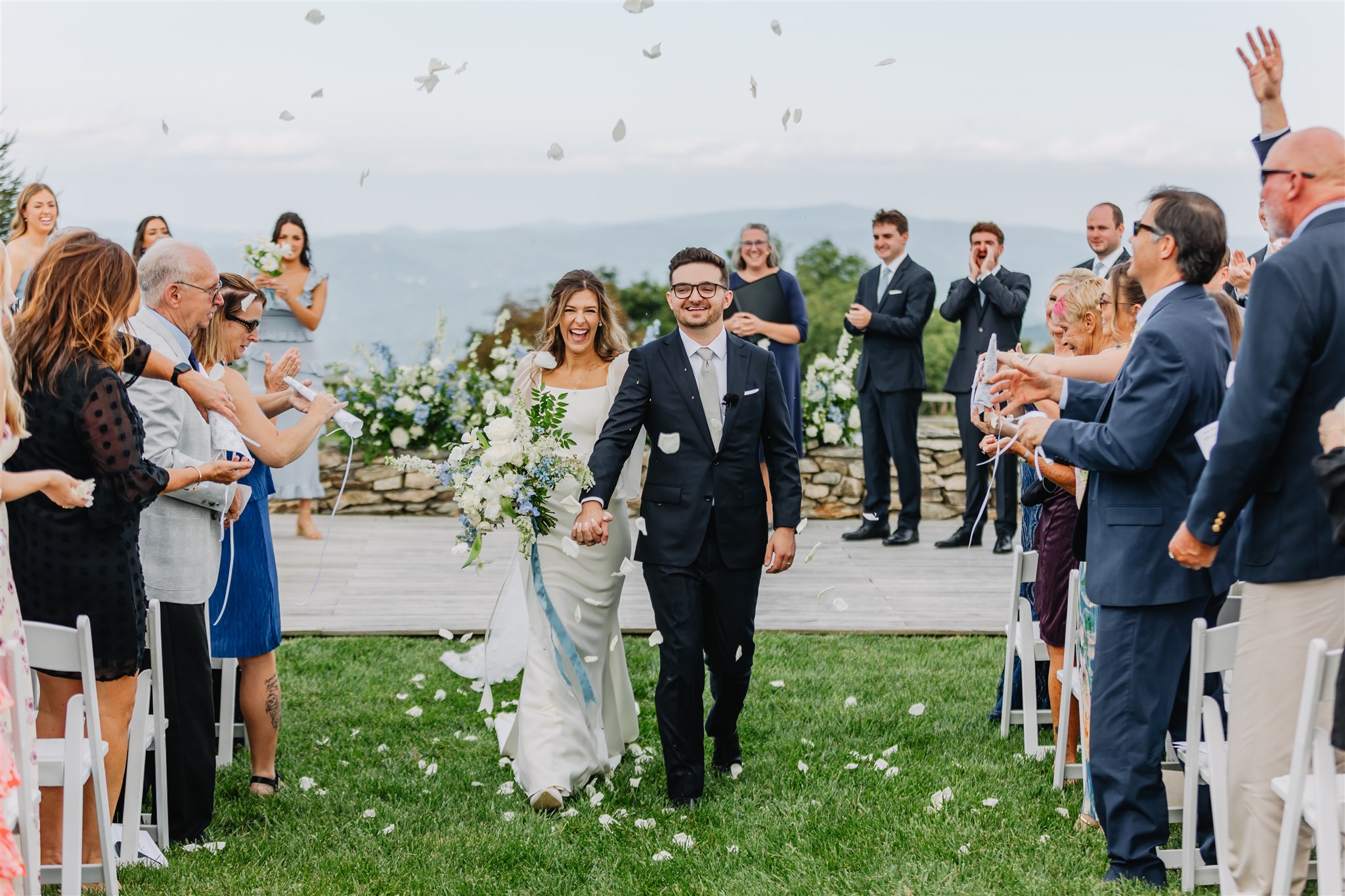A couple exiting their wedding ceremony with guests tossing petals.