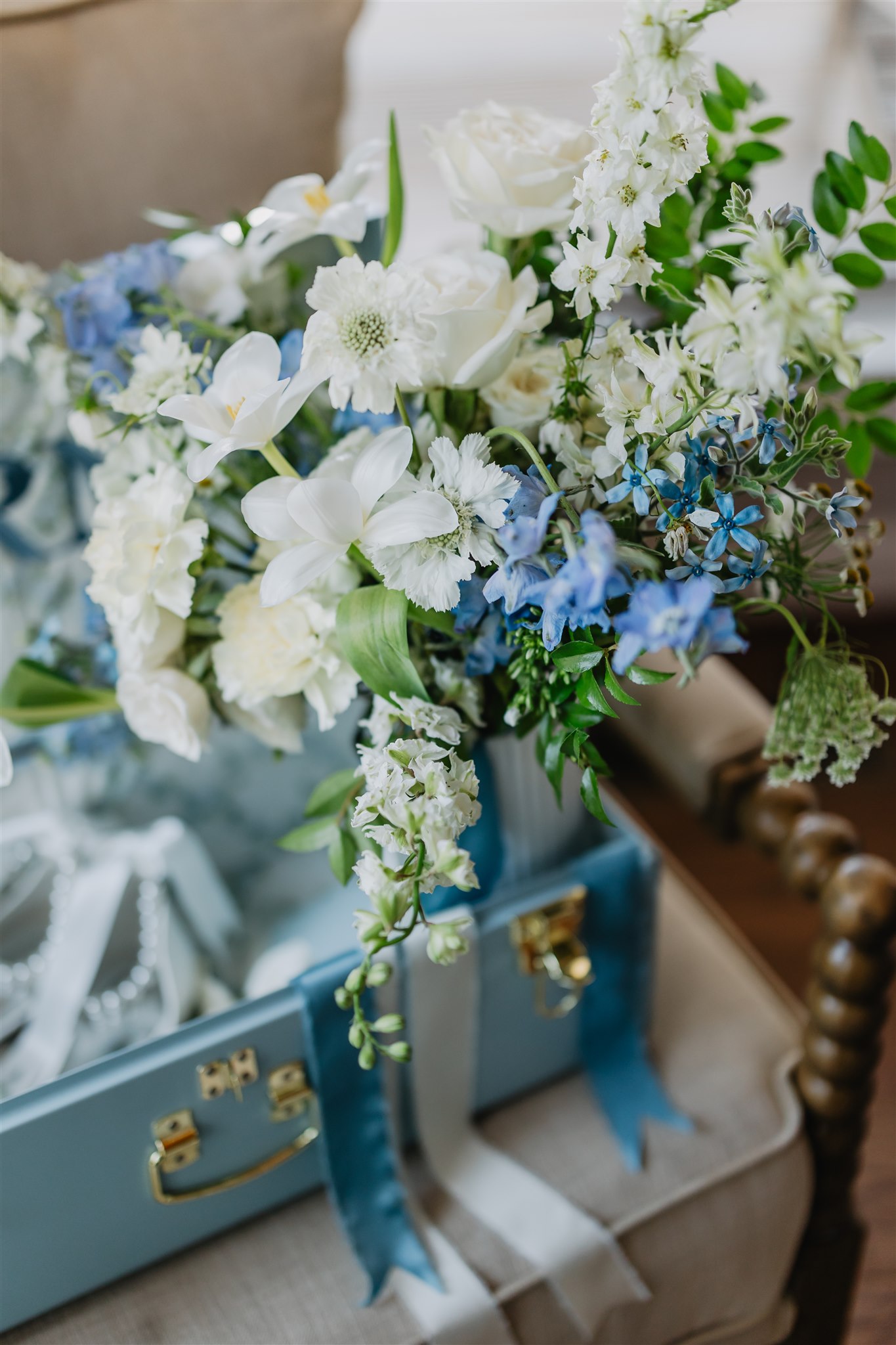 Wedding flowers in a blue suitcase style box with hues of blue and white in the floral design.